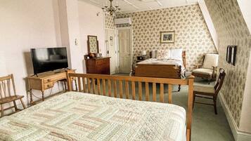 A bedroom with a bed, a television, a dresser, a chair, and a desk.