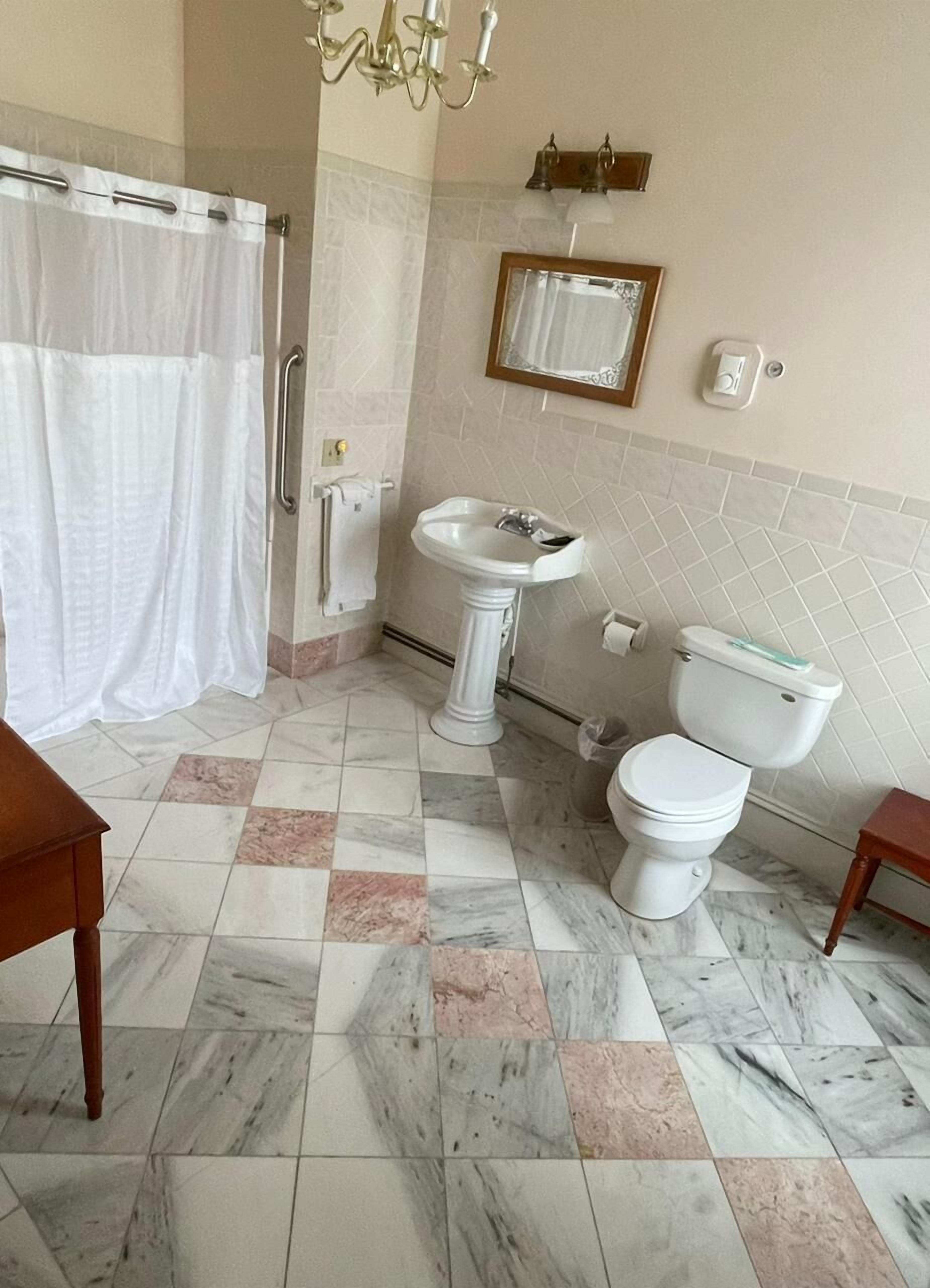 A bathroom with a shower, sink, toilet, and a chandelier.