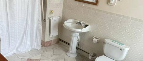 A bathroom with a shower, sink, toilet, and a chandelier.
