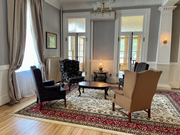 A room with a patterned carpet, a chandelier, and a table with a lamp. - Brandon Inn (Brandon)