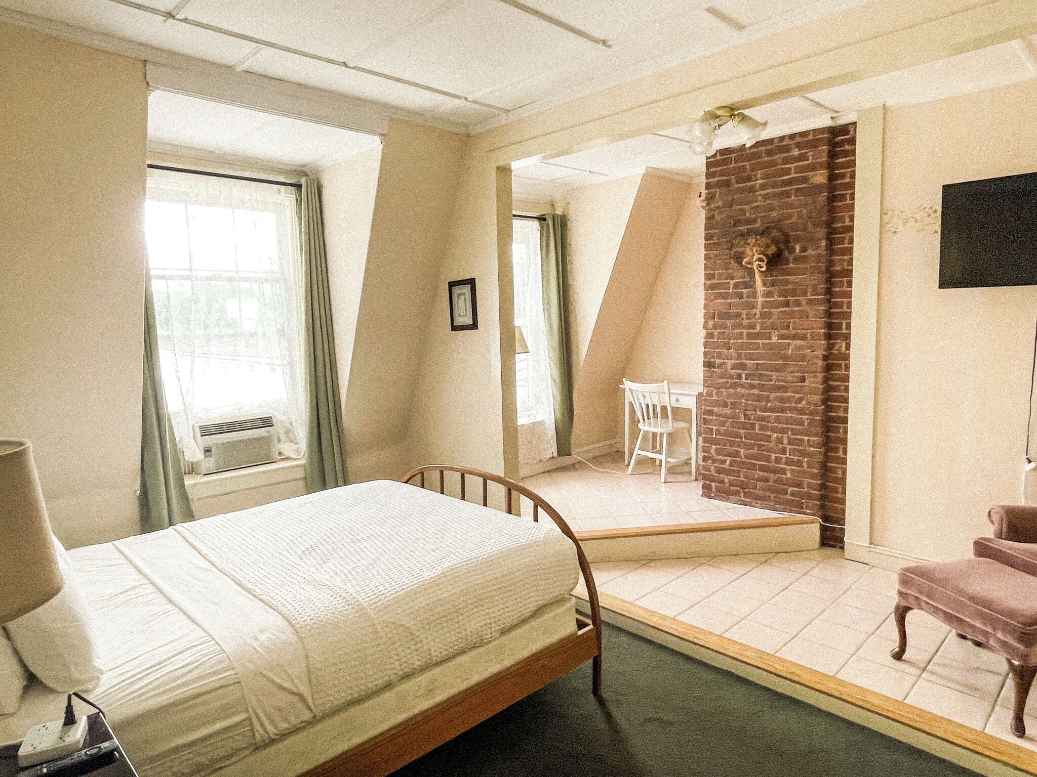 A bedroom with a bed, a desk, a chair, and a TV.