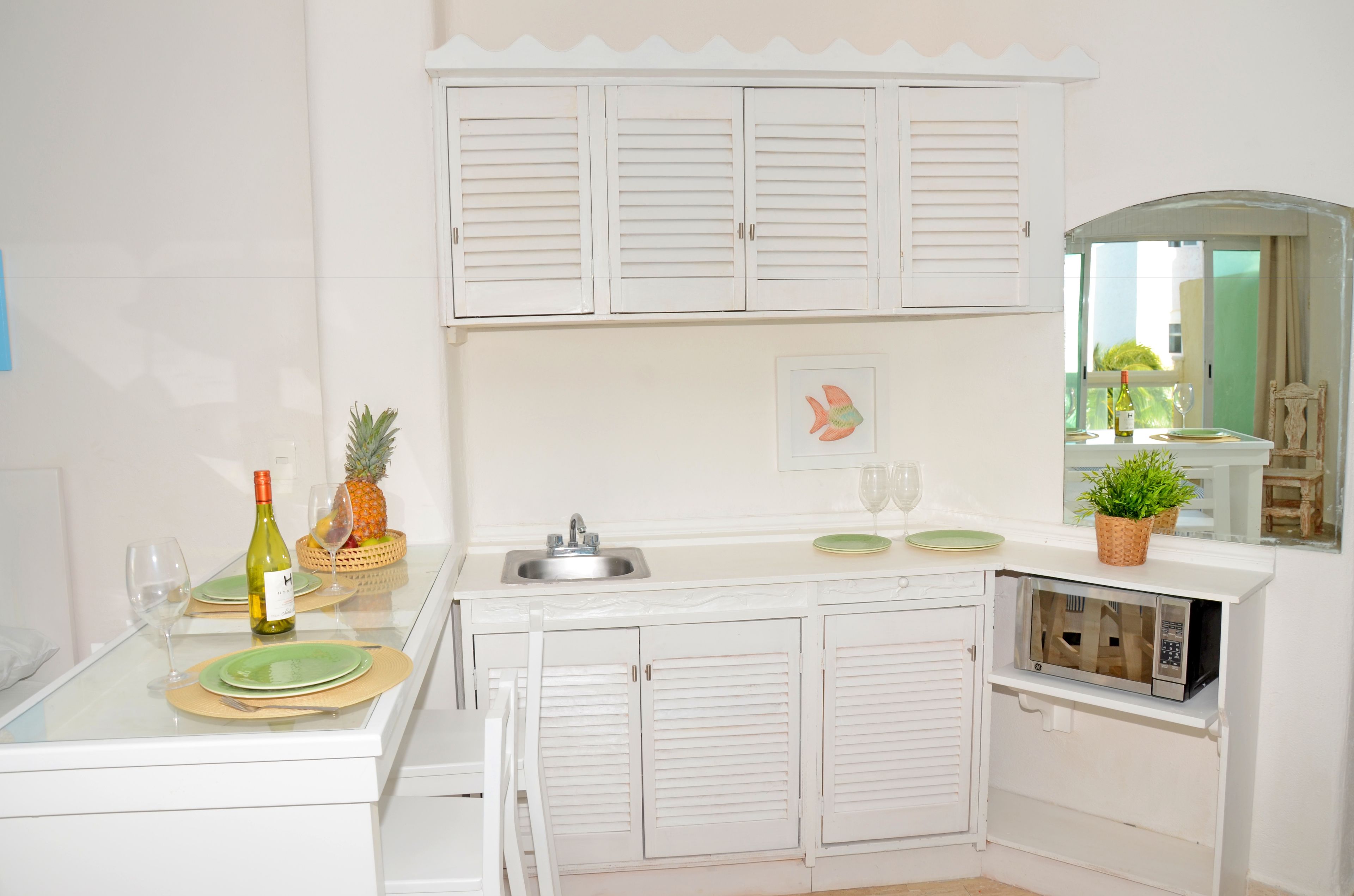 A modern kitchen with white cabinetry, a built-in microwave, and a sink.