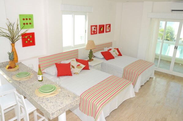 Une chambre d’hôtel avec deux lits, un coin repas et une grande fenêtre.