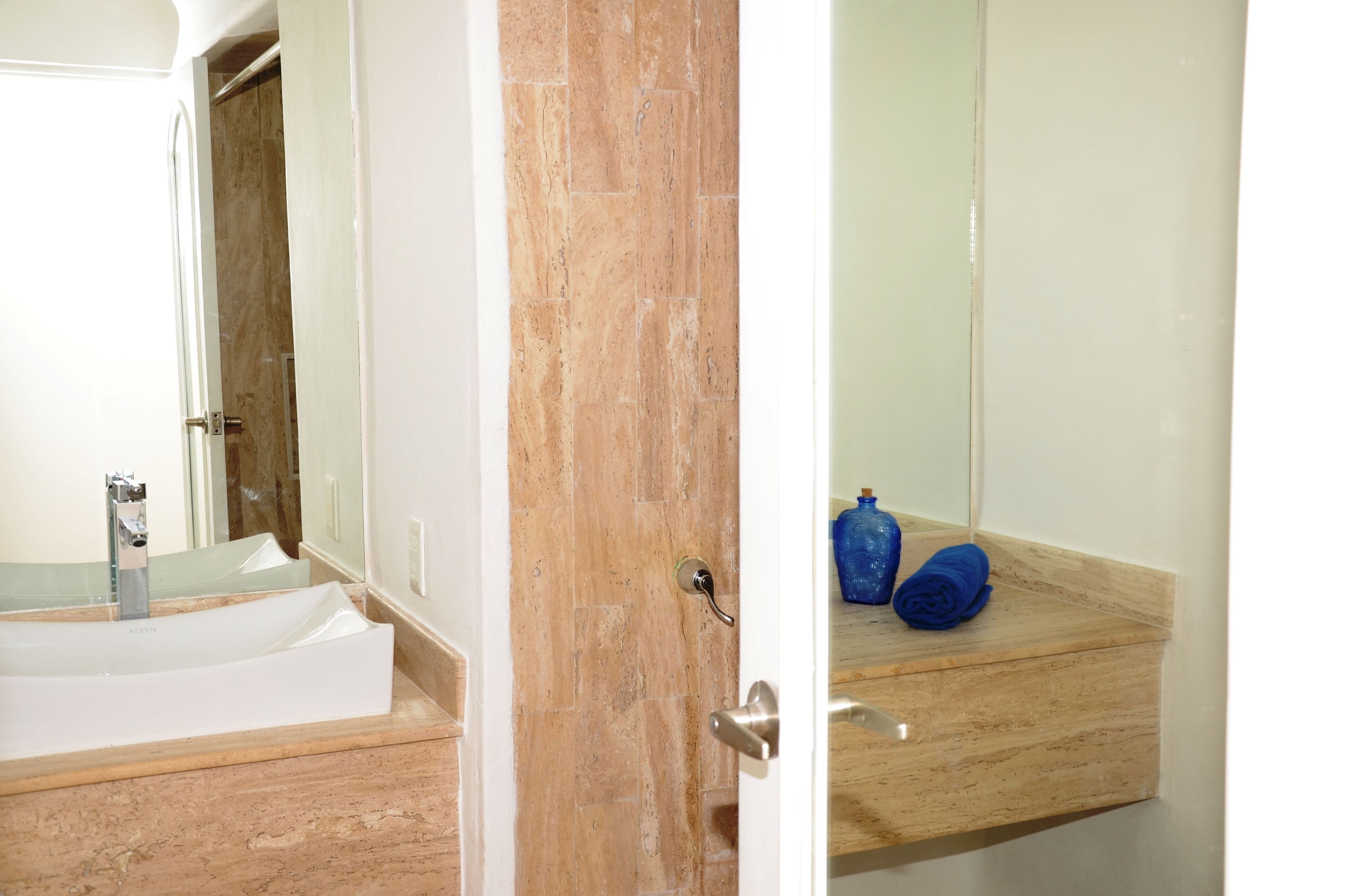 A bathroom with a marble sink, a mirror, and a wooden vanity.