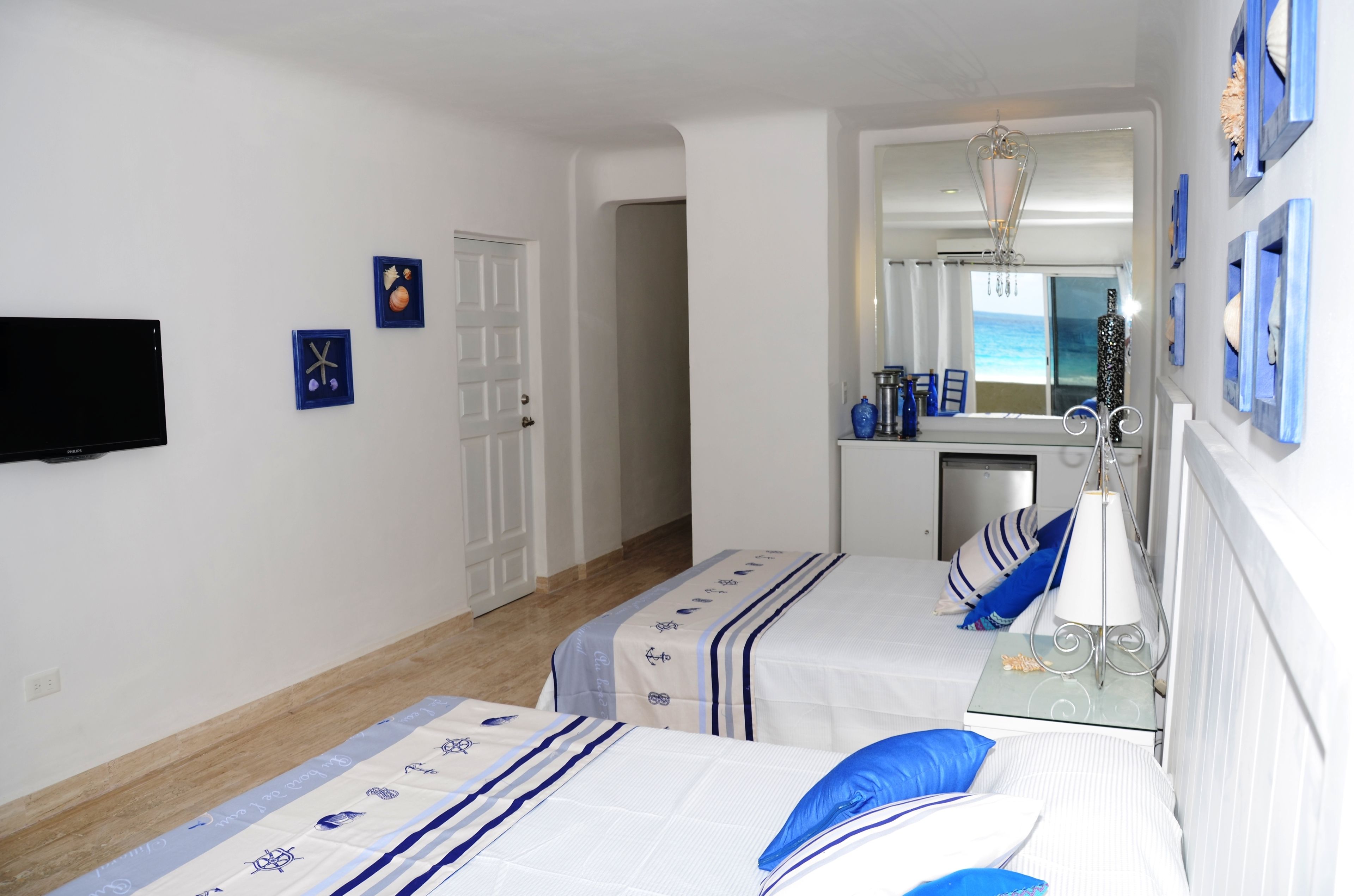 A bedroom with two beds, a television, and a bathroom visible through an open door.