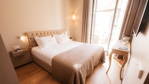 A hotel room with a large bed, a bedside table, a desk, and a window with curtains. - Hotel Casa Peya - Adults Only (Palafrugell)