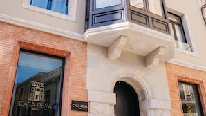 A hotel with a prominent entrance, a balcony, and a clear view of the interior through the windows. - Hotel Casa Peya - Adults Only (Palafrugell)