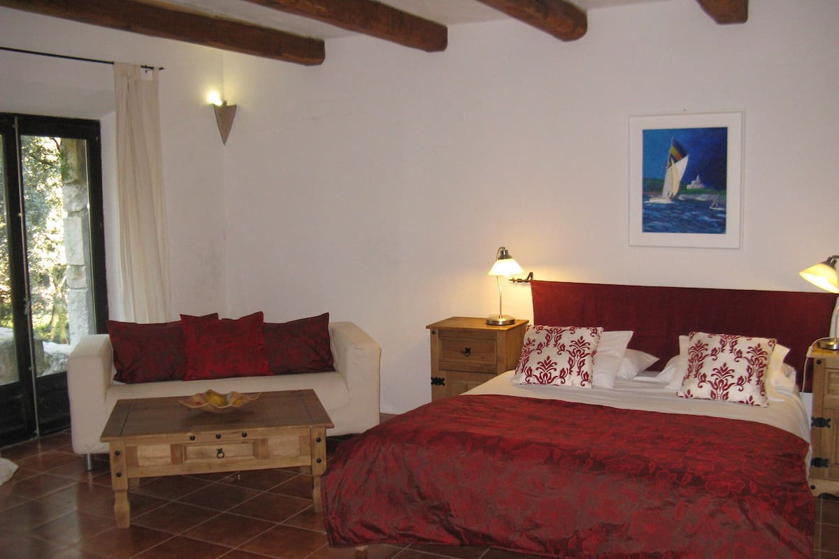 Une chambre à coucher avec un lit, un canapé, une table de chevet et une fenêtre.