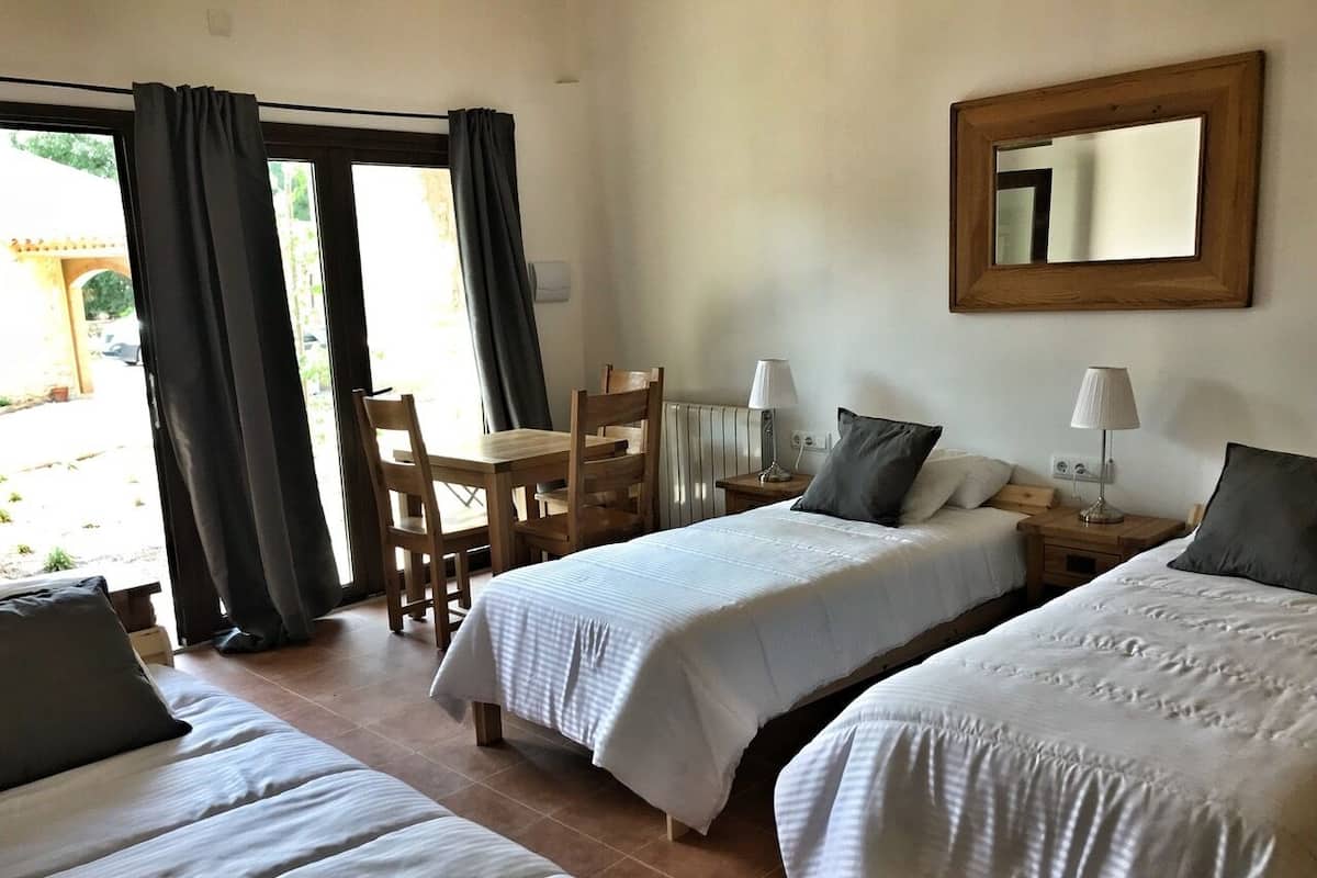 Une chambre d’hôtel avec deux lits, une chaise, une table et une fenêtre avec des rideaux.