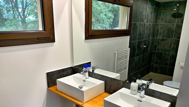 A modern bathroom with two sinks, wooden vanity, and a large mirror. - Hotel Mas Pelegri (Serinya)