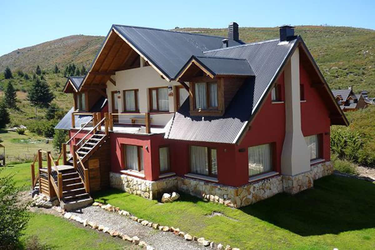 A two-story house with a stone foundation, a wooden staircase, and a balcony.