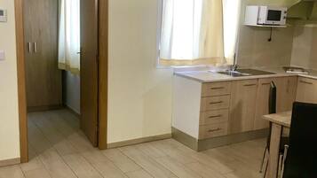 A compact kitchen with a built-in microwave, a sink, and a wooden table.