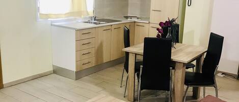 A compact living space with a kitchenette, a dining area, and a sofa.