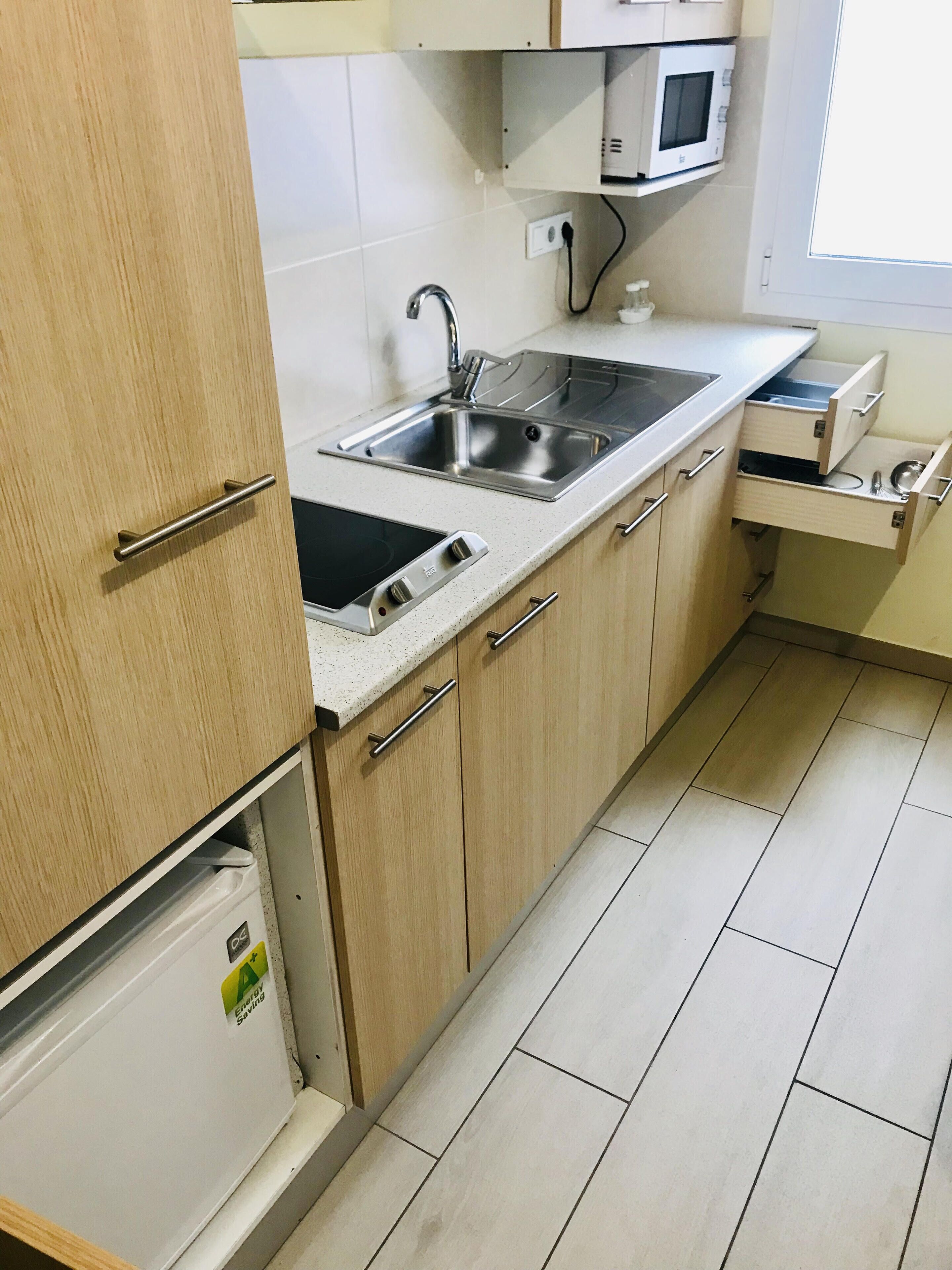 Eine Küche mit einem doppelten Spülbecken, Holzschränken, einer Mikrowelle und einem Kühlschrank.