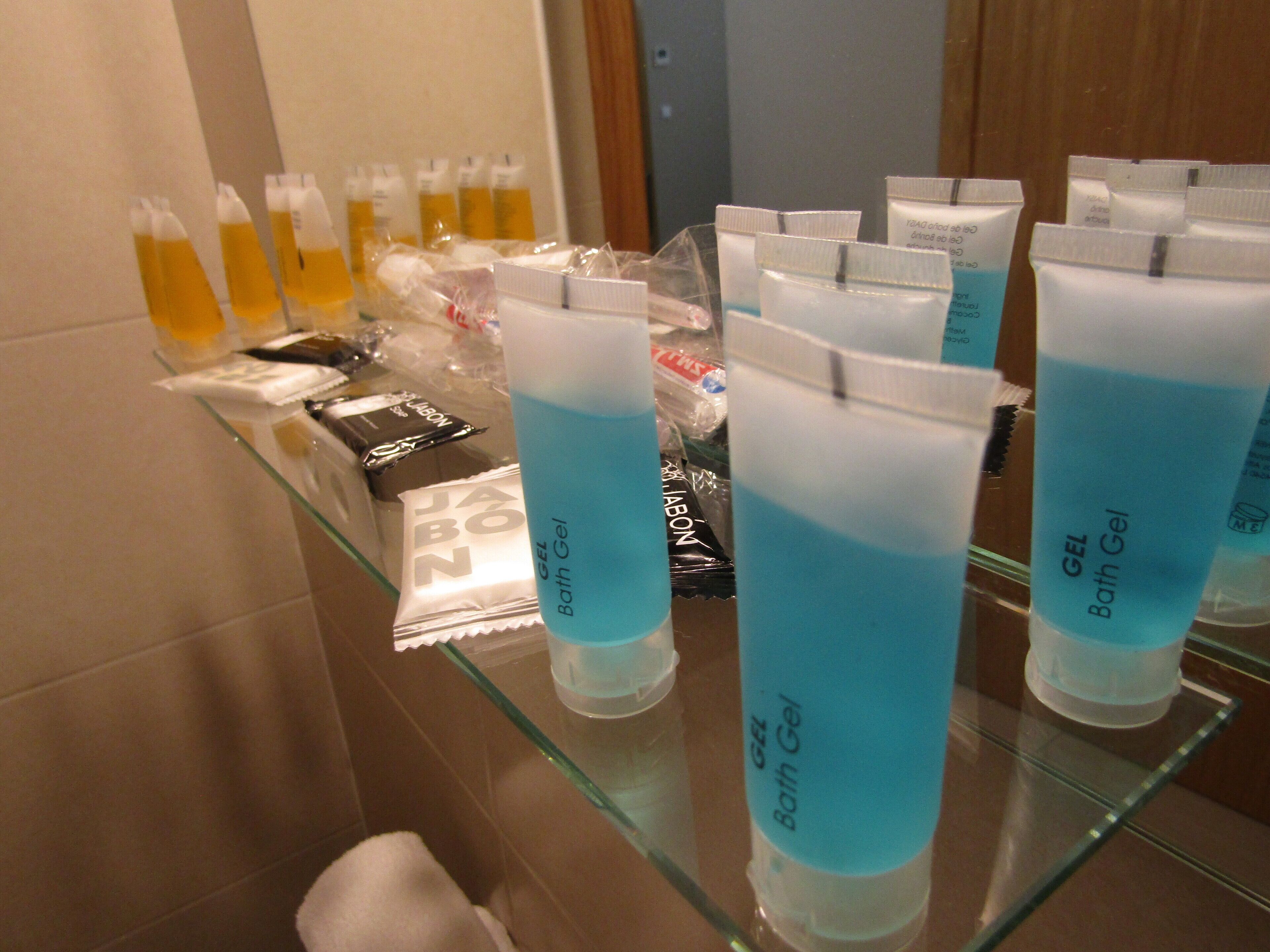 Una repisa de baño con distintos artículos de aseo, incluyendo botellas de gel y jabón líquido.