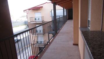 Un balcone con pavimento in piastrelle, soffitto in legno e ringhiera in metallo.