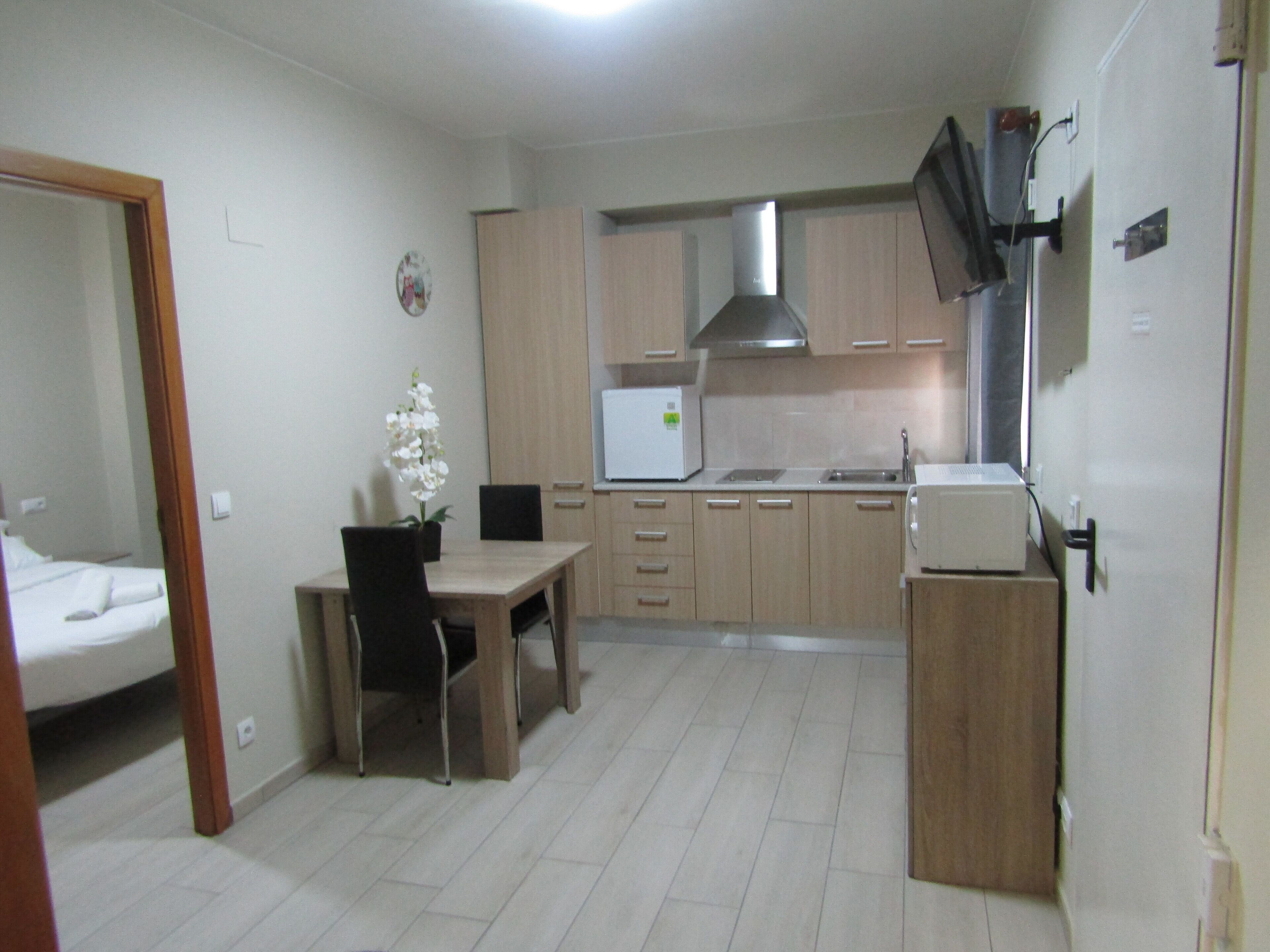 A compact kitchen with wooden cabinets, a white refrigerator, a stove, and a dining area with a table and chairs.