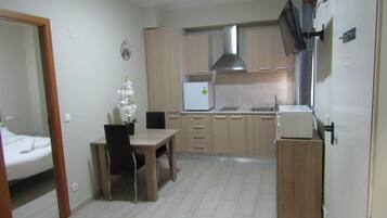 A compact kitchen with wooden cabinets, a white refrigerator, a stove, and a dining area with a table and chairs.