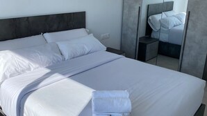 Un dormitorio moderno con una cama grande, una mesita de noche, un espejo y un armario.