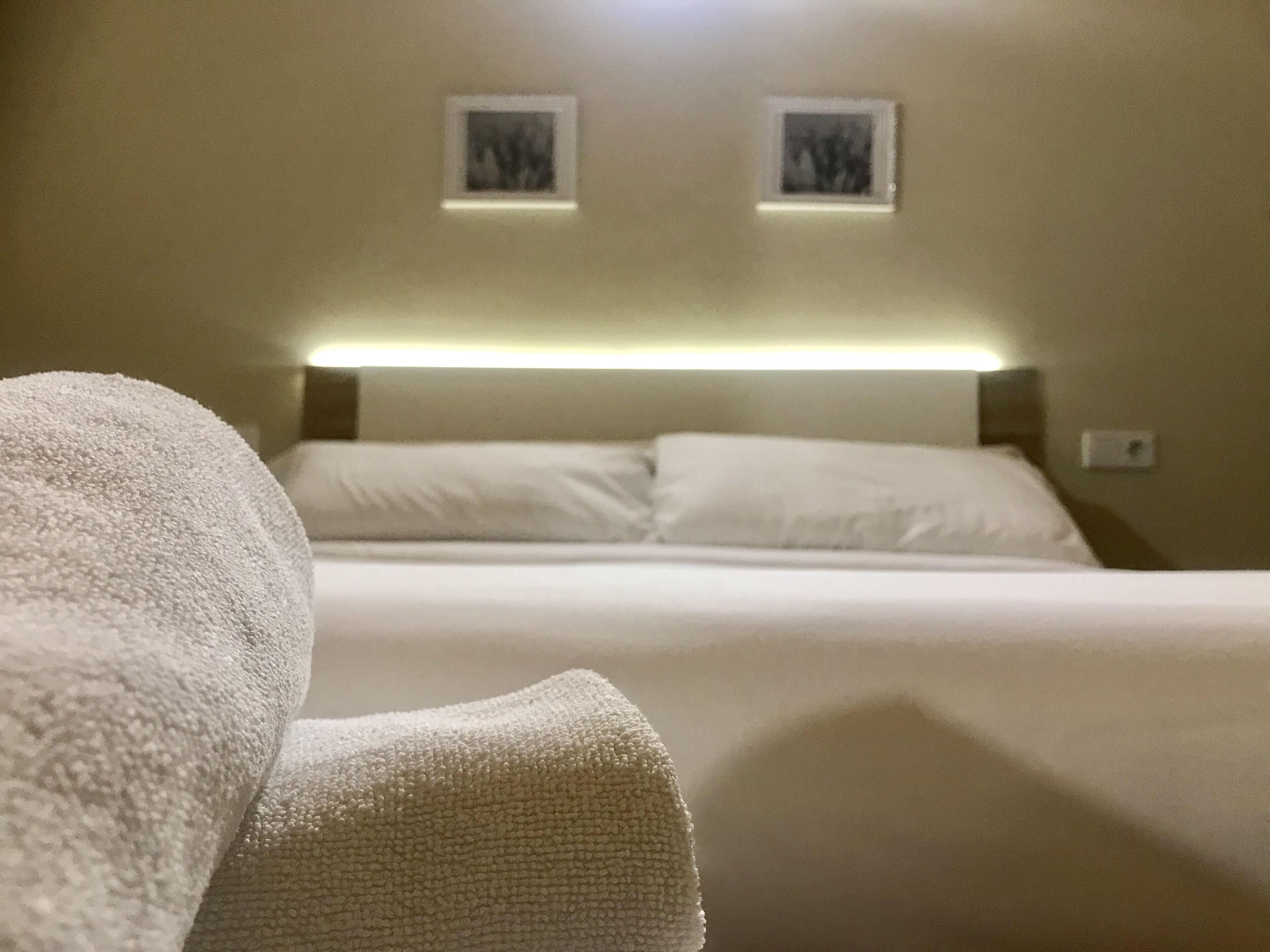 Une chambre d’hôtel avec un lit, deux cadres photos accrochés au mur et une lampe de chevet.