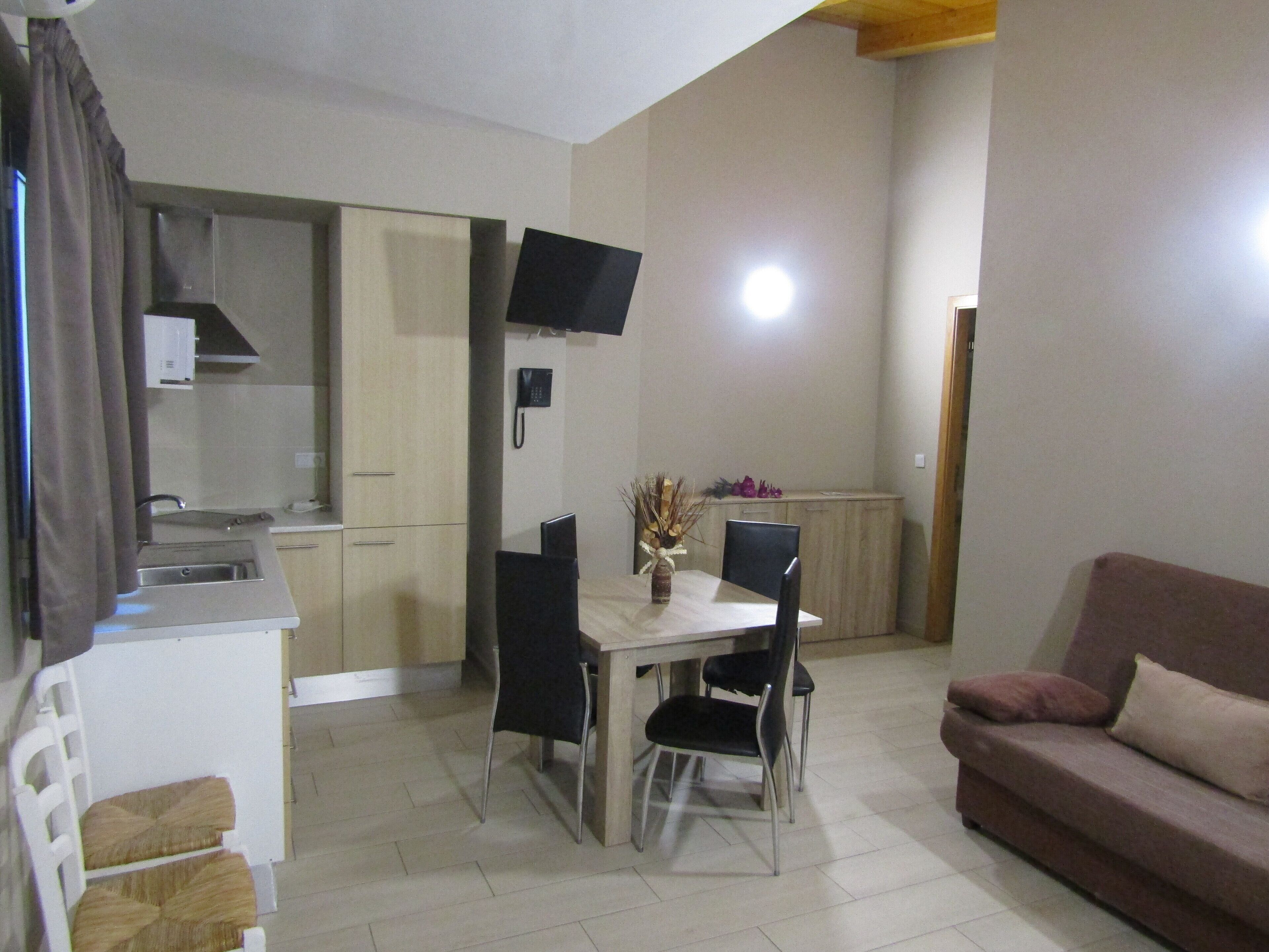 Un espacio habitable compacto con kitchenette, comedor y sofá.
