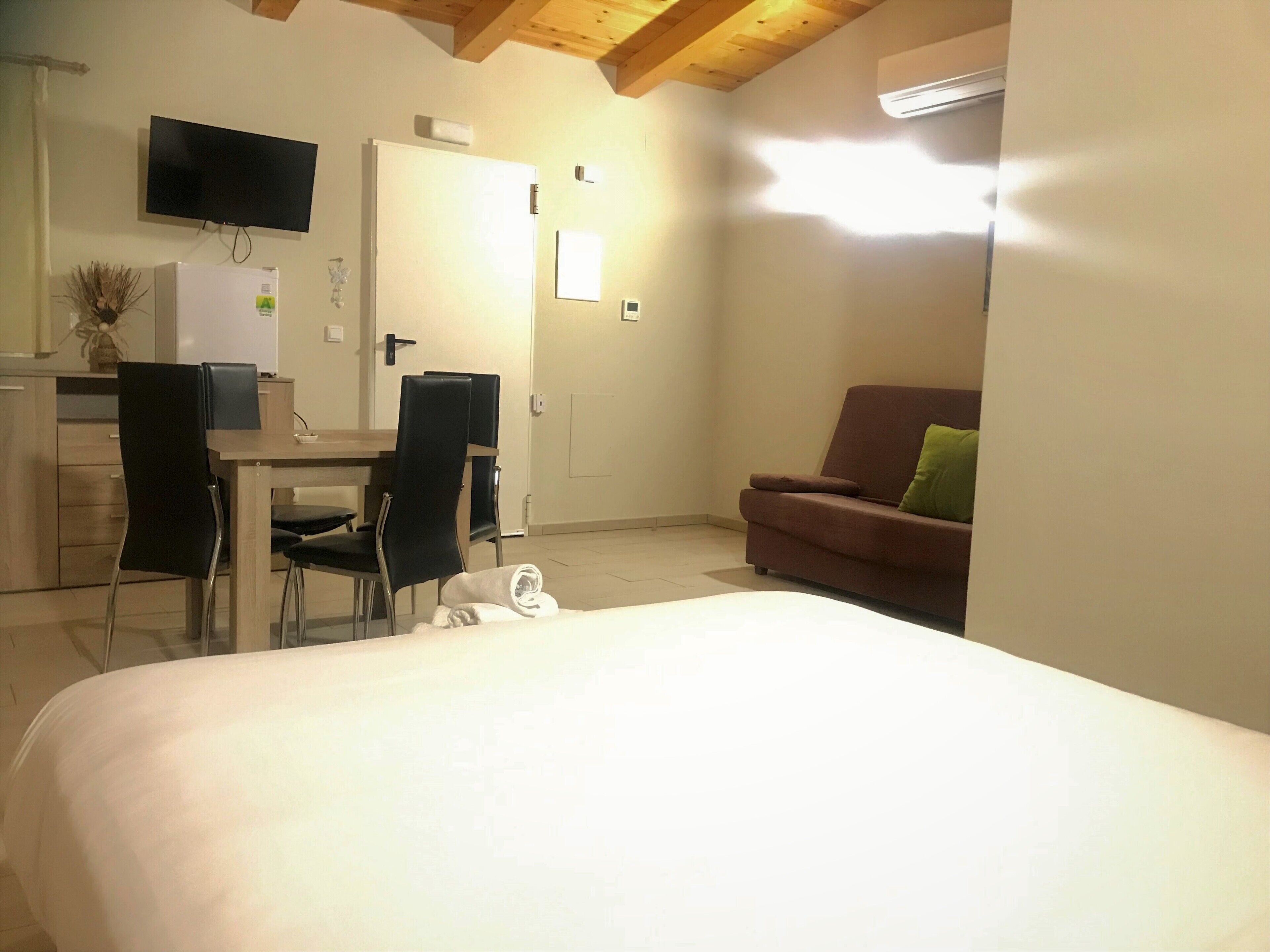 Una habitación de hotel con una cama, un escritorio con sillas, un televisor y un sofá.