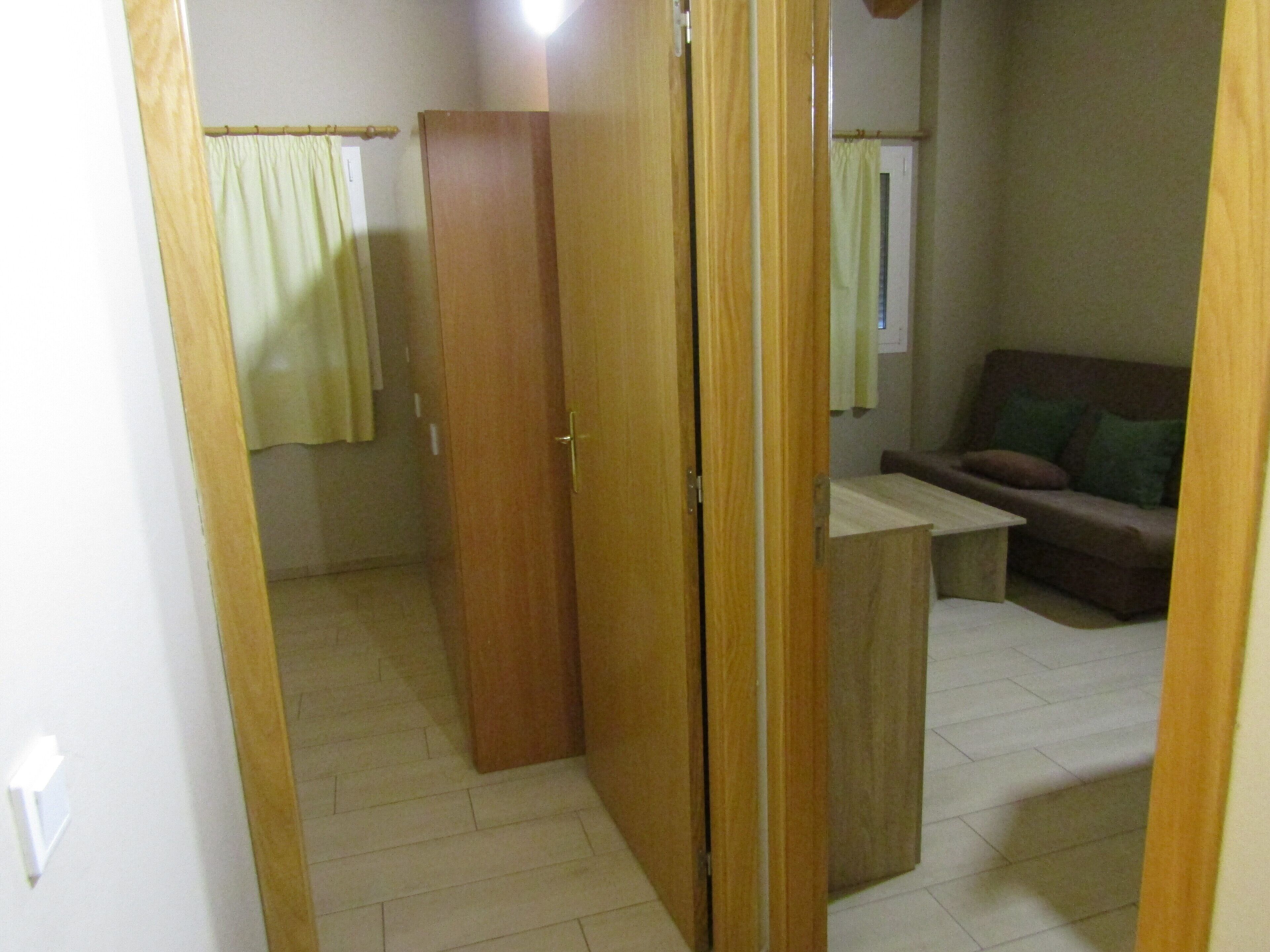 Une pièce comprenant une armoire en bois, une petite table en bois, un canapé et un rideau.