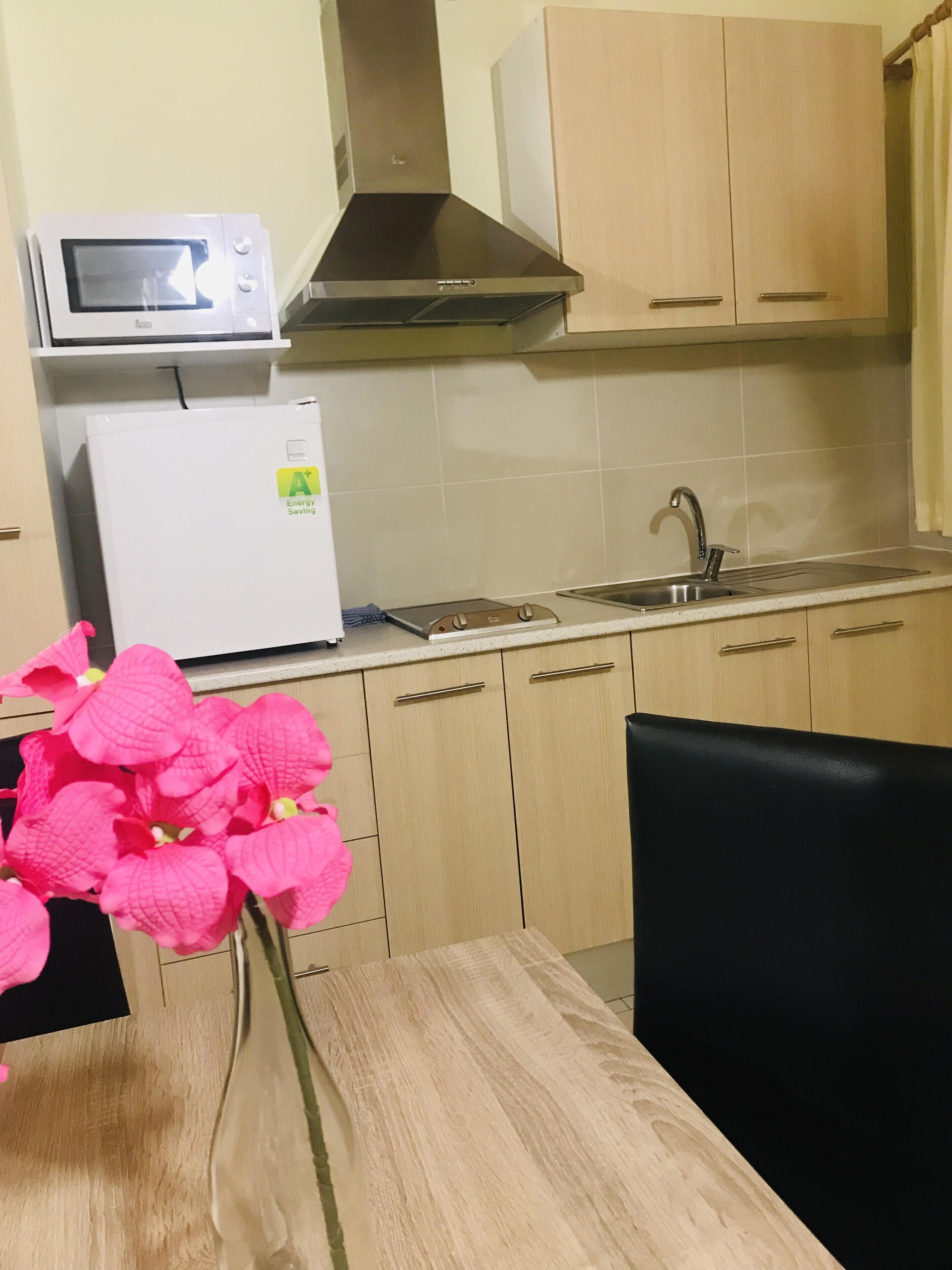 A kitchen with a microwave, refrigerator, sink, and wooden cabinets.