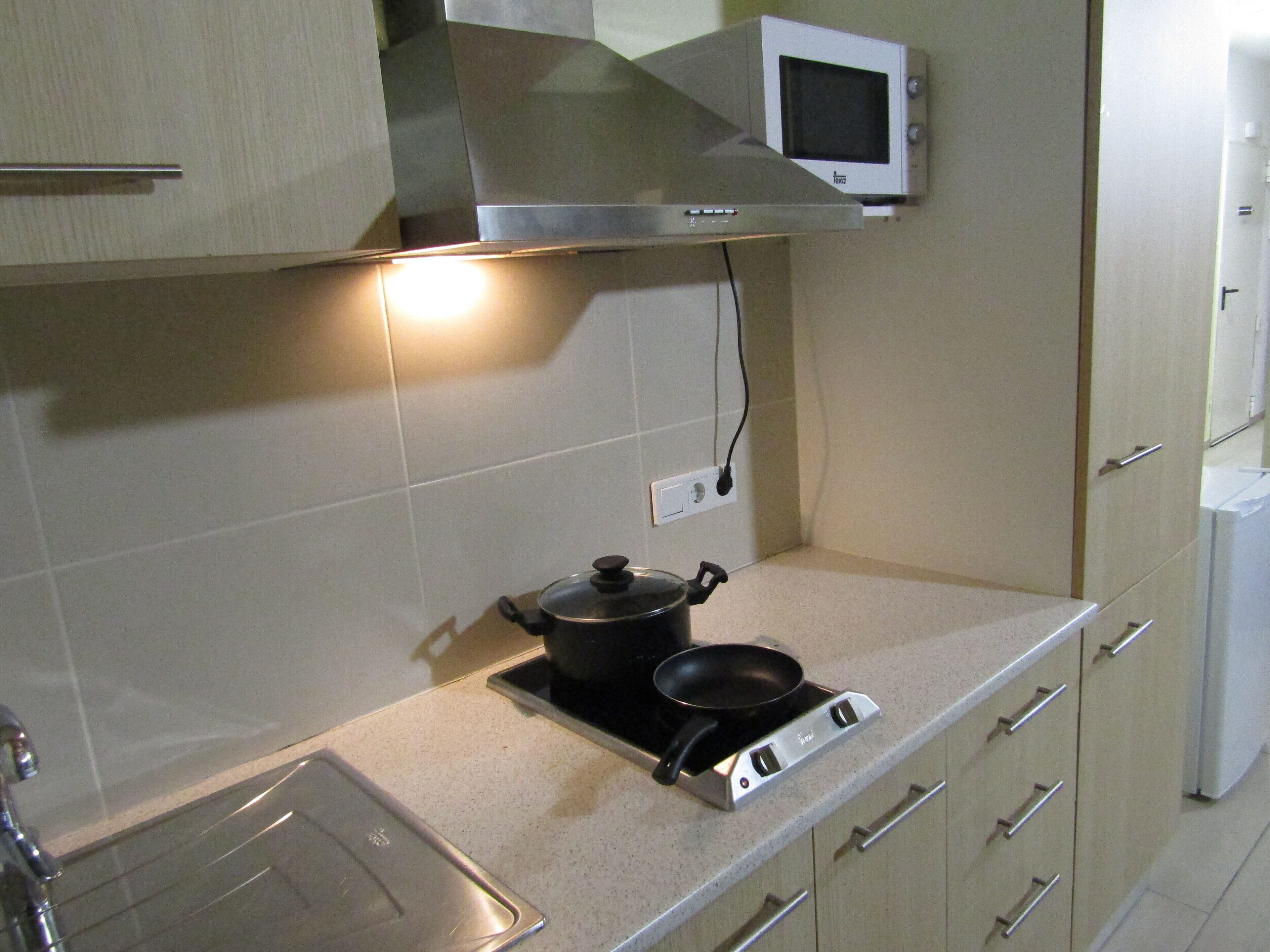 Une cuisine équipée d’une cuisinière, d’une casserole, d’un four à micro-ondes et d’un évier.