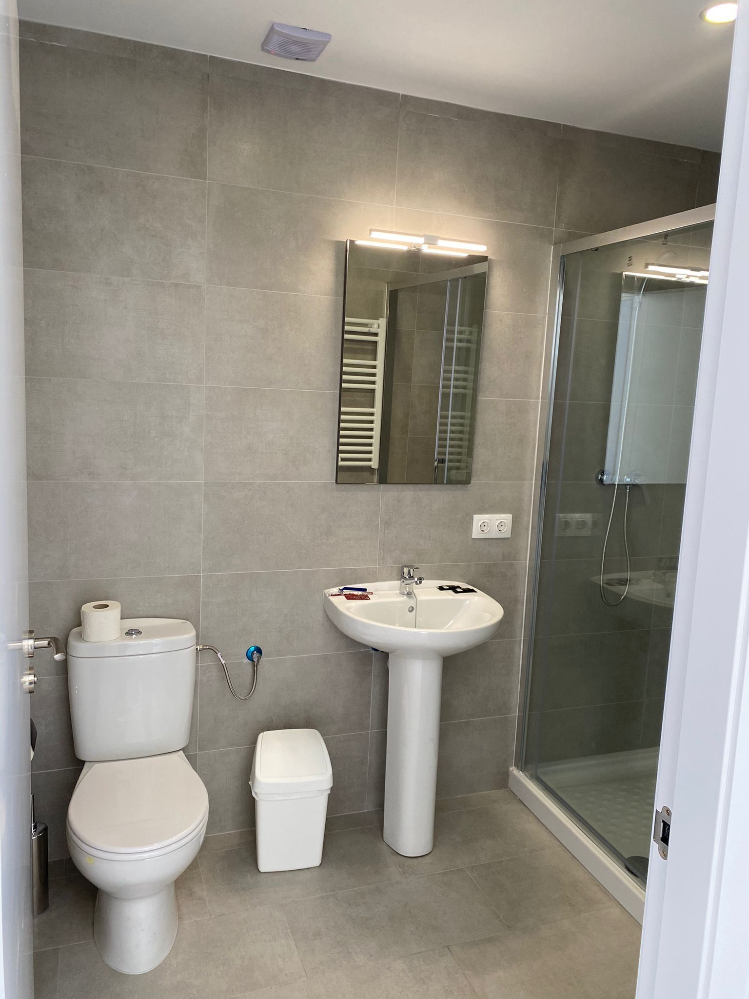 Ein modernes Badezimmer mit Toilette, Waschbecken und Duschkabine aus Glas.