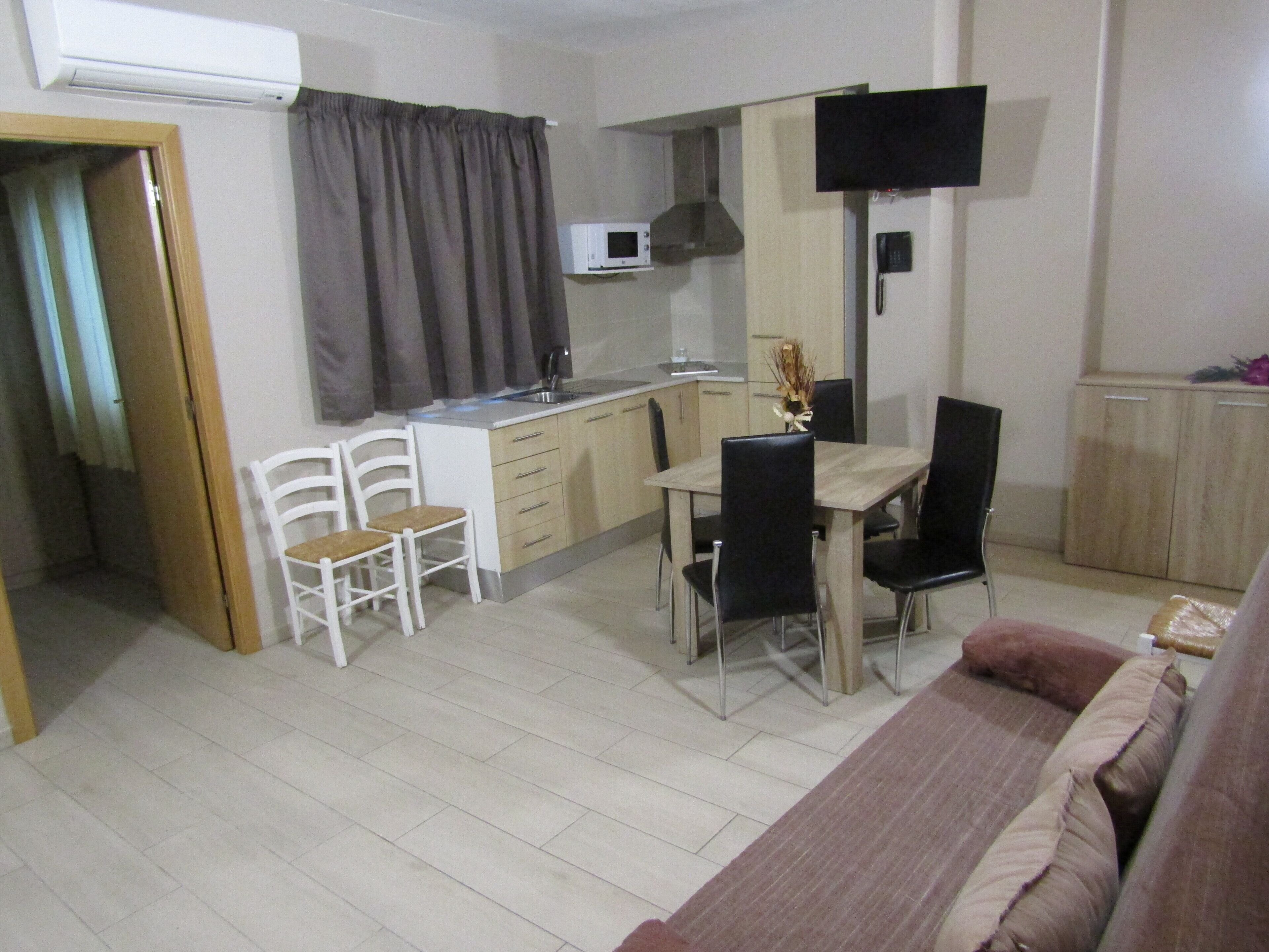 Un espacio habitable compacto con kitchenette, comedor y zona de estar.