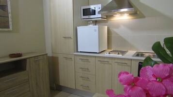 Eine Küche mit hellen Holzschränken, einem weißen Kühlschrank, einer Mikrowelle und einem Spülbecken.