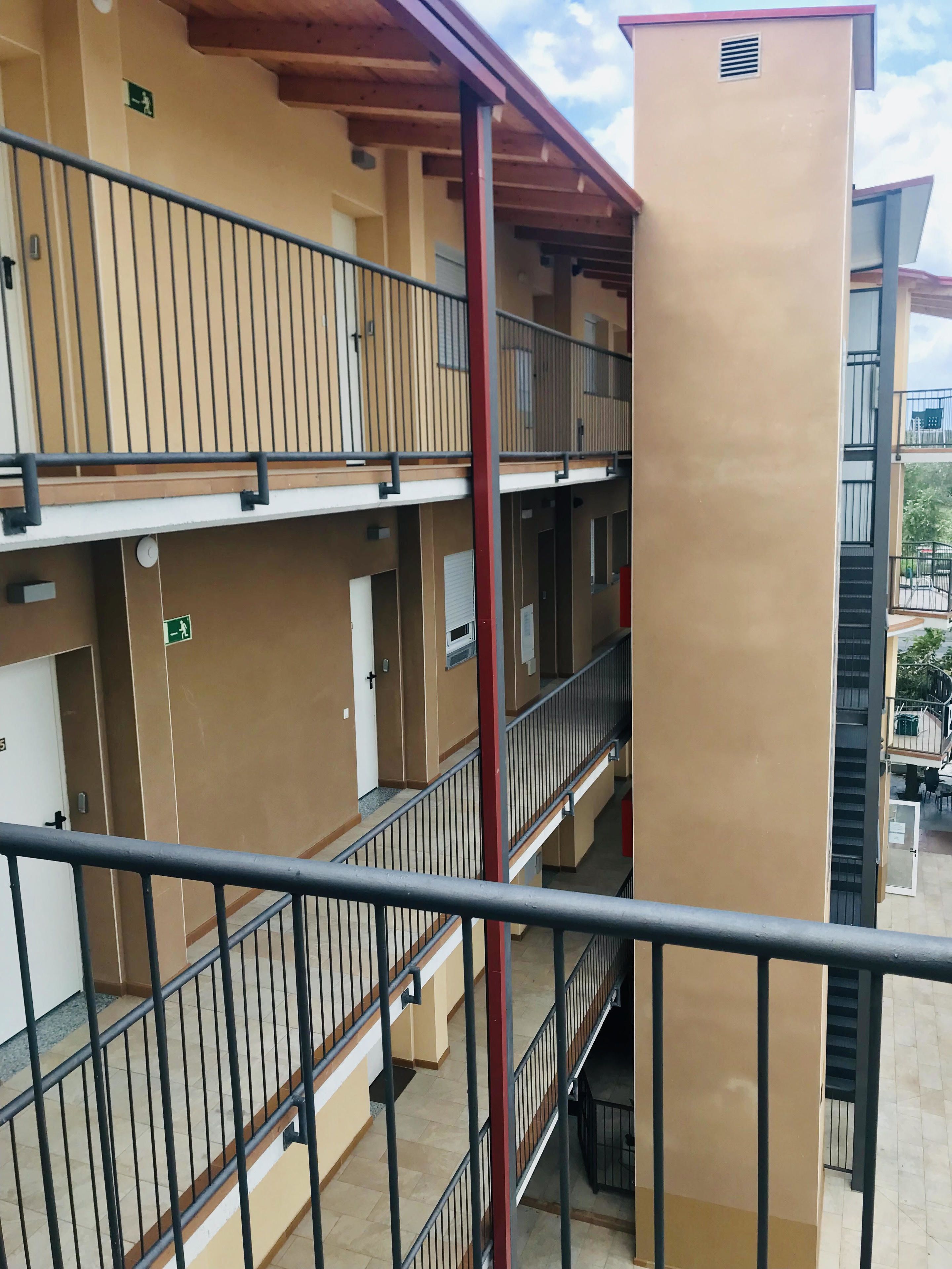A multi-story building with balconies, a staircase, and a red railing.