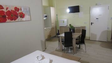 Habitación de hotel con cama, escritorio, silla, televisor y puerta.