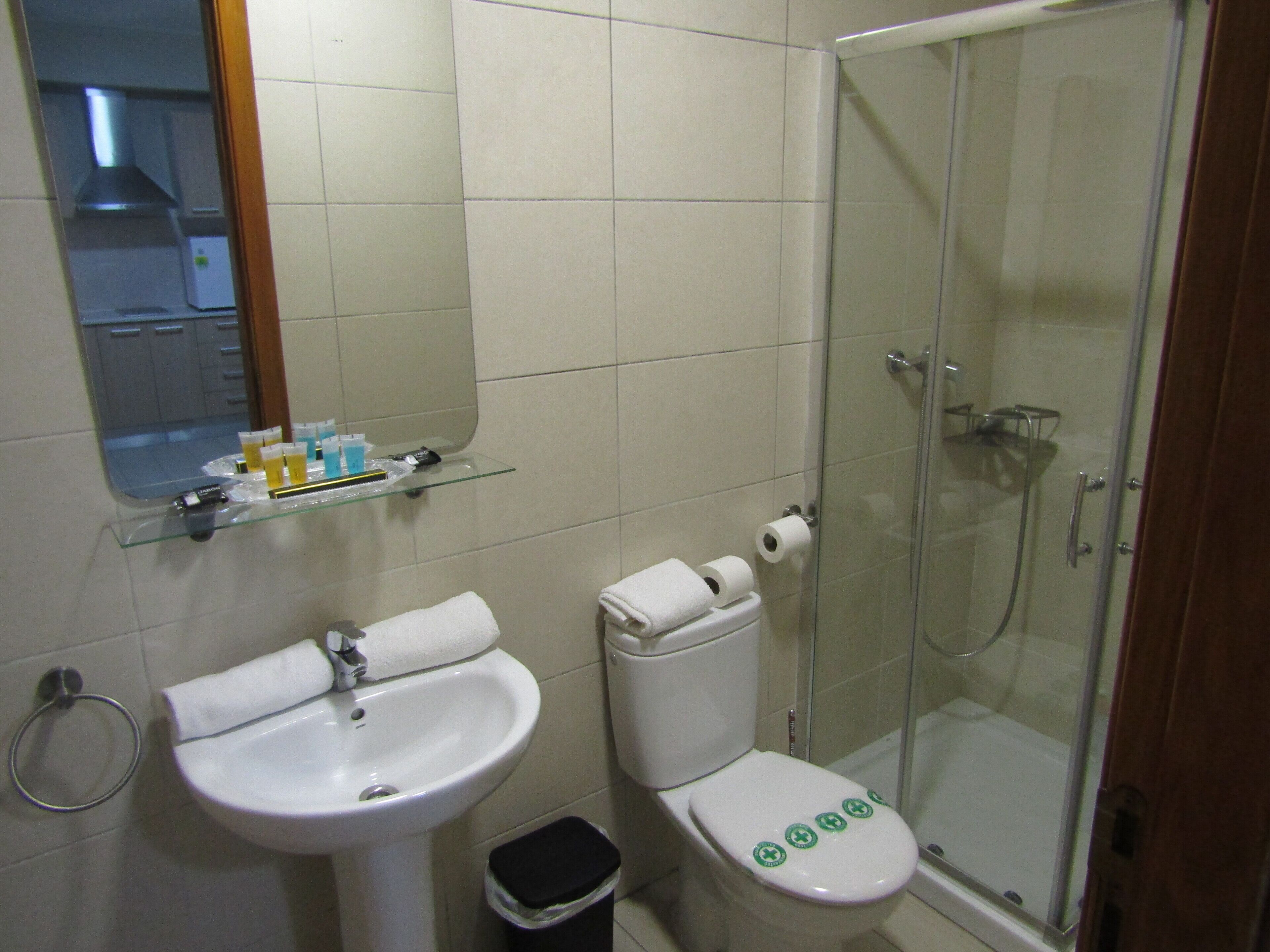 Baño con lavamanos, inodoro y cabina de ducha de vidrio.