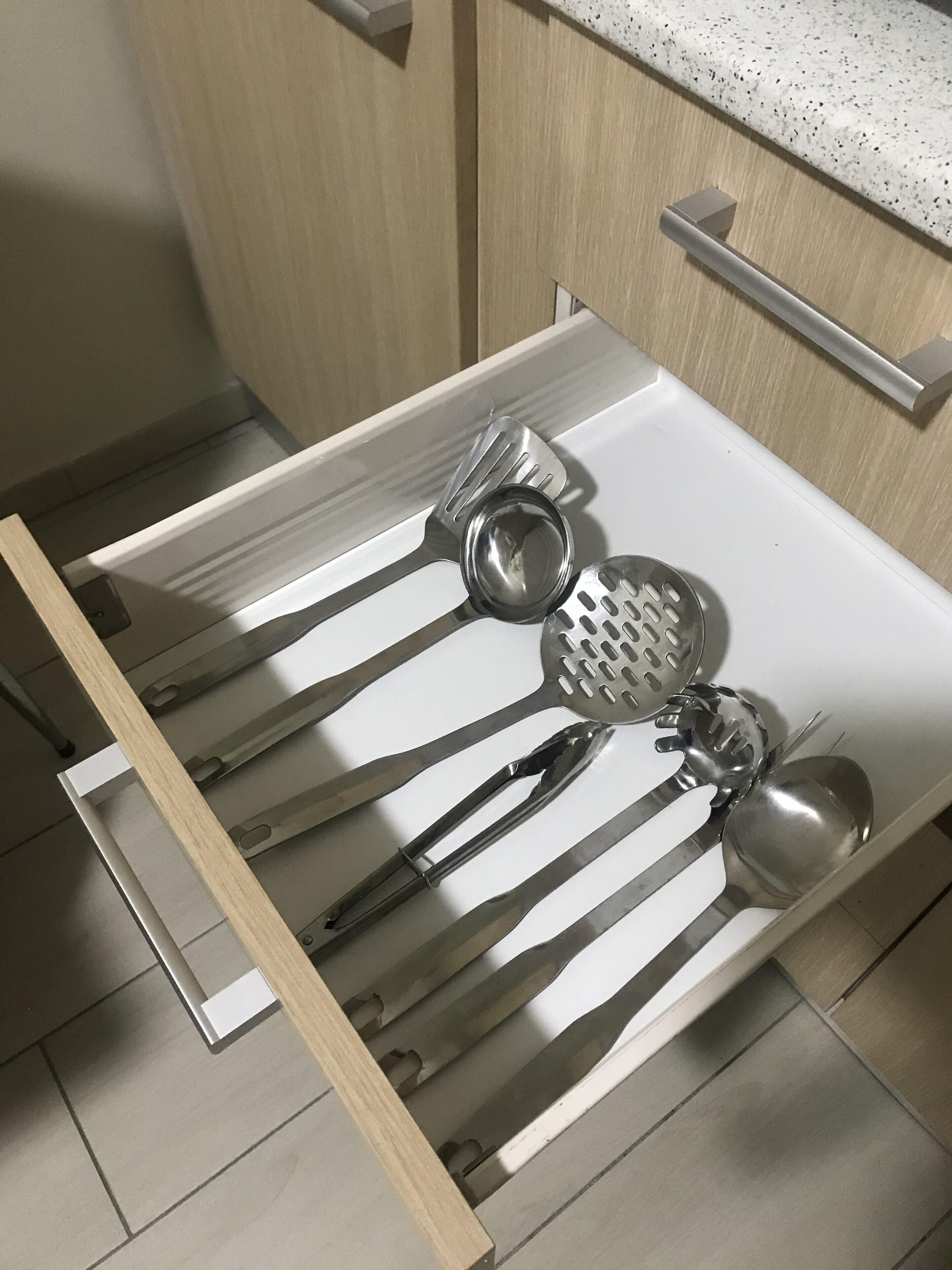 A kitchen drawer with stainless steel utensils.