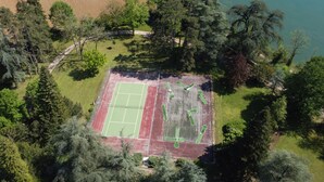 An aerial view of a tennis court surrounded by dense trees.