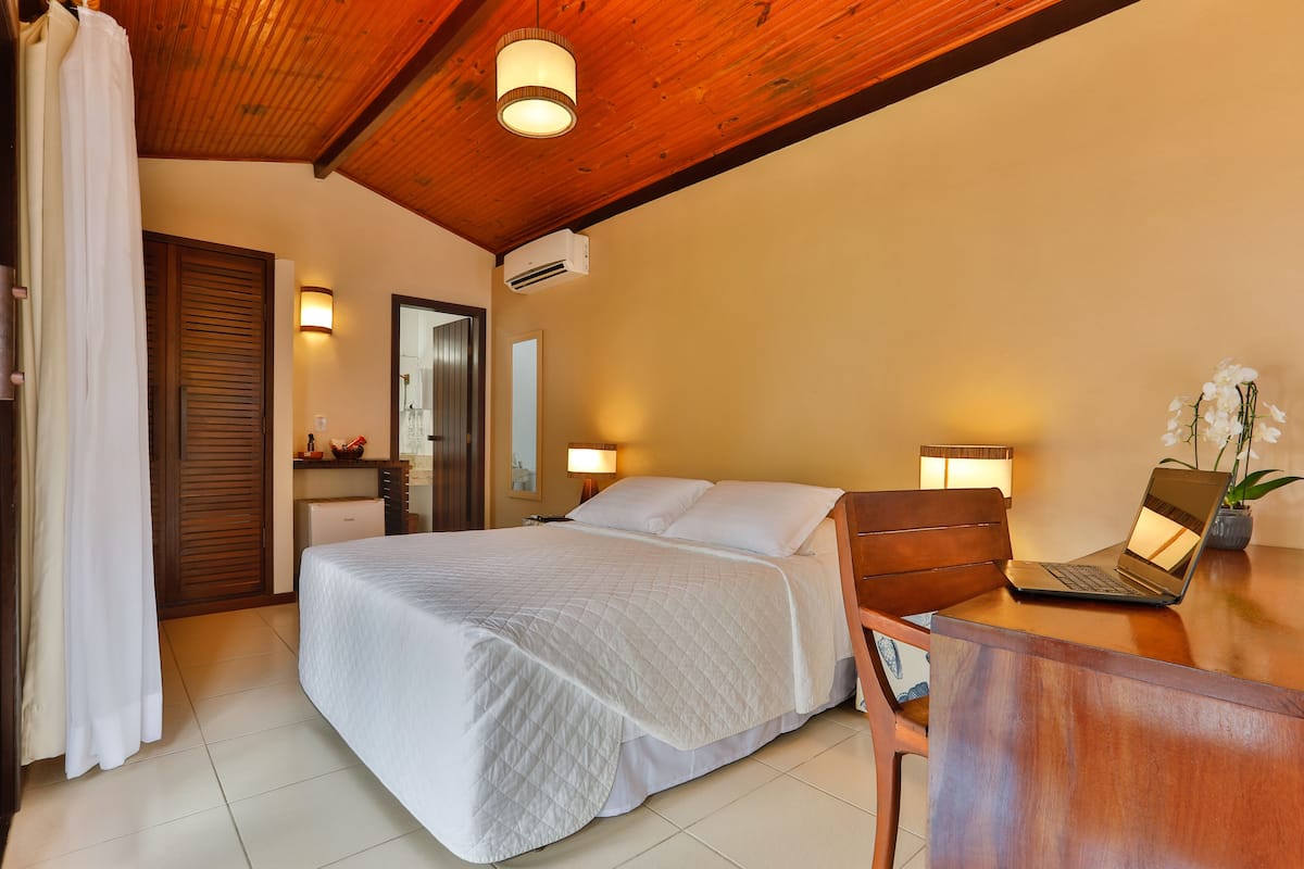 A bedroom with a bed, bedside table, and a laptop.