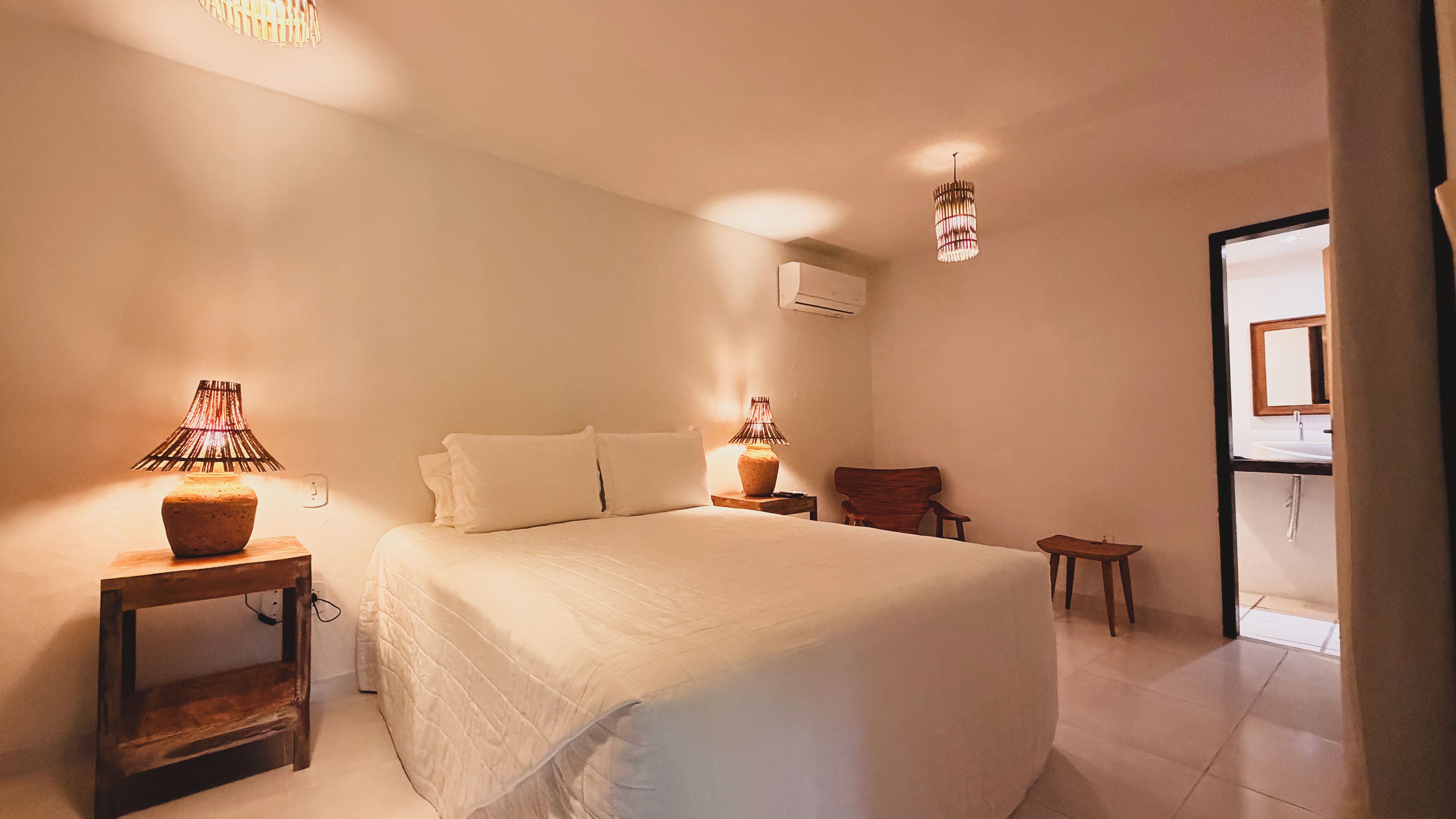 Een hotelkamer met een groot bed, twee nachtkastjes met lampen, een stoel en uitzicht op de badkamer.