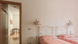 Un dormitorio con dos camas, una silla y dos lámparas de pared.