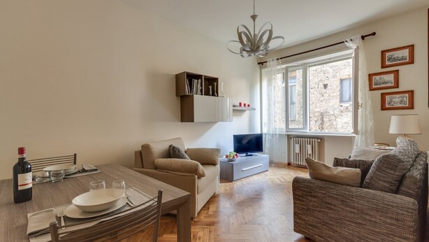 Una sala de estar con una mesa de comedor, sofá, televisor y estanterías.