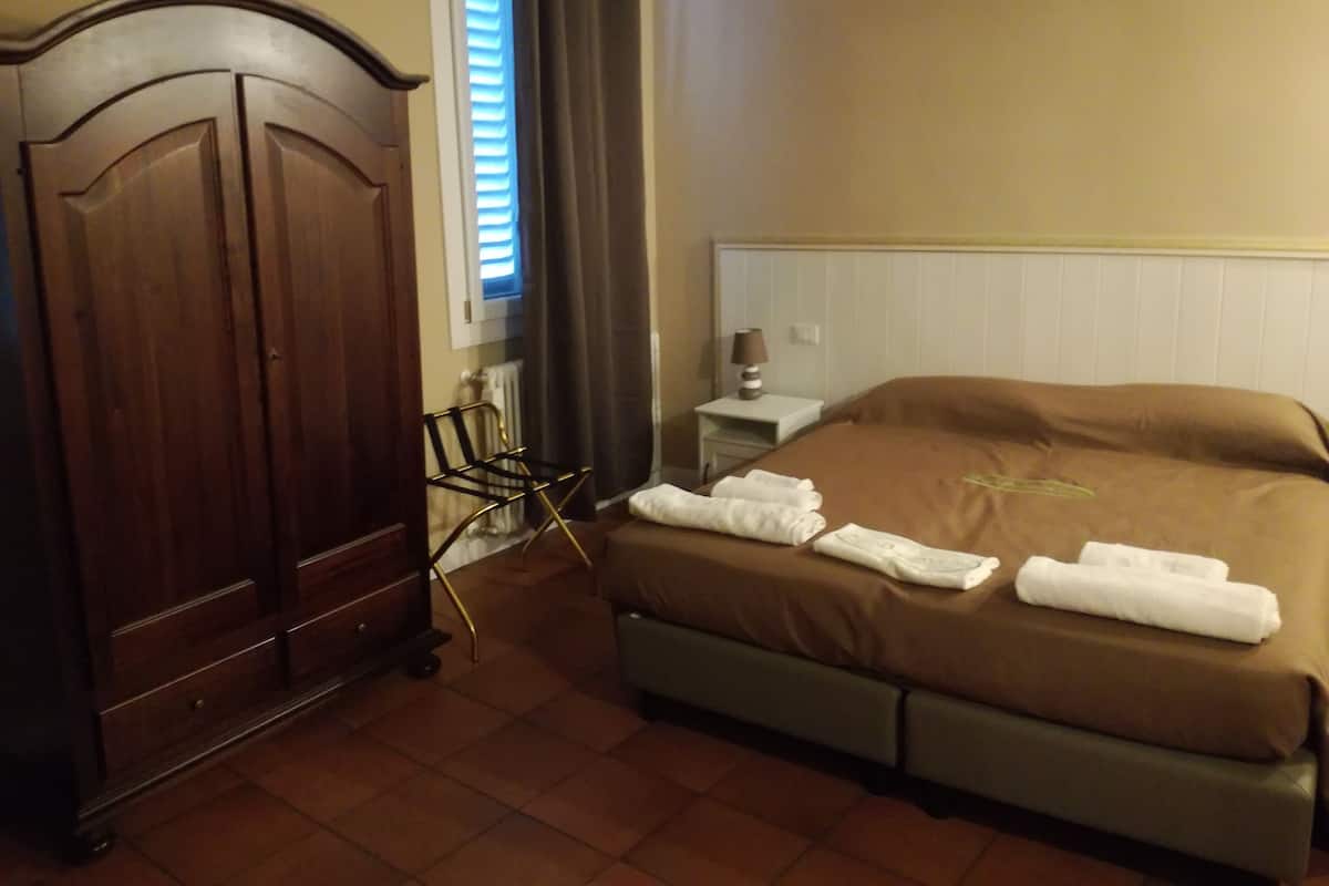 Ein Hotelzimmer mit einem Bett, einem Holzschrank, einem Sessel und einem Nachttisch mit Lampe.