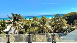 Een balkon met vrij uitzicht op een strand en de oceaan.