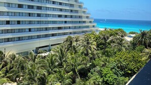 Een meerlaags hotel met een modern design, gelegen nabij een strand met helderblauw water en weelderige begroeiing.