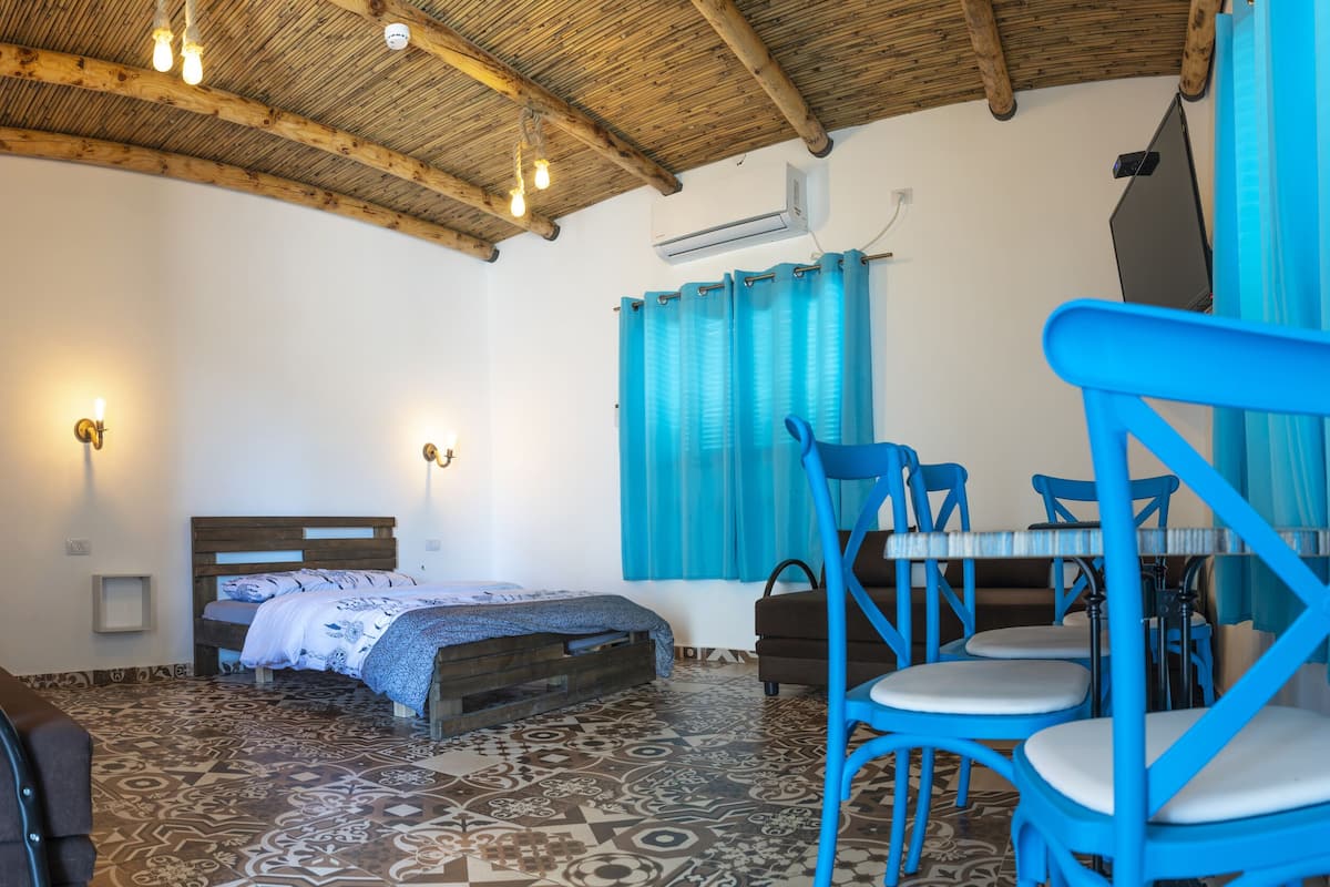 A room with a bed, a desk, and blue chairs.