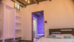 A bedroom with a wooden bed, a built-in shelf unit, and a small bicycle. - Old School (Ein Qiniyye)