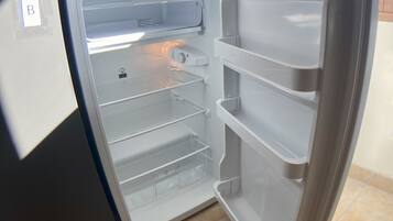 Un refrigerador abierto con múltiples estantes y un compartimento congelador.
