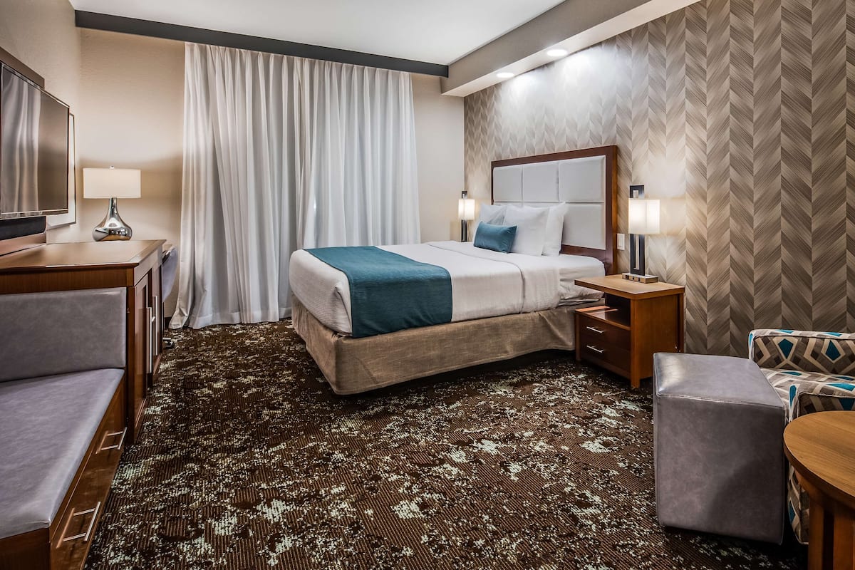 A hotel room with a bed, a desk, a chair, and a small table.
