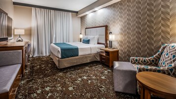 Una habitación de hotel con una cama, un escritorio, una silla y una mesita.
