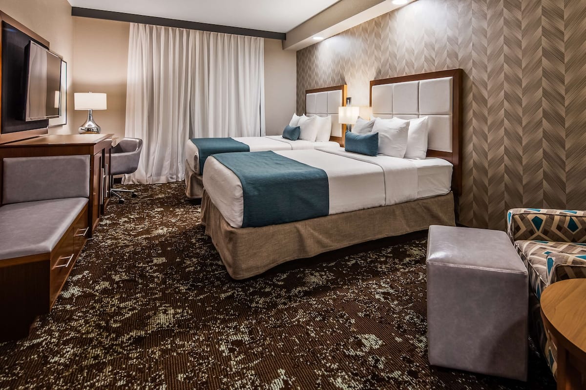 A hotel room with a large bed, two bedside tables, a desk, a chair, and a patterned carpet.